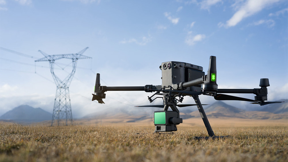 Industrial drone applications high-voltage power lines in a rural landscape.