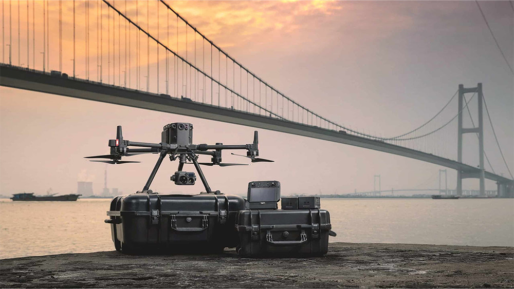 Professional industrial drone applications with camera equipment set up near a bridge during sunset.