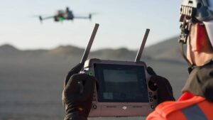 Drone operator controlling a DJI drone during an aerial survey in a remote landscape.